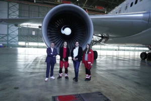 Hangar bei Austrian Airlines: Ausbilder, zwei Auszubildende und ein Vertirebsmitarbeiter von Lucas-Nülle stehen vor dem Triebwerk eines Flugzeugs.