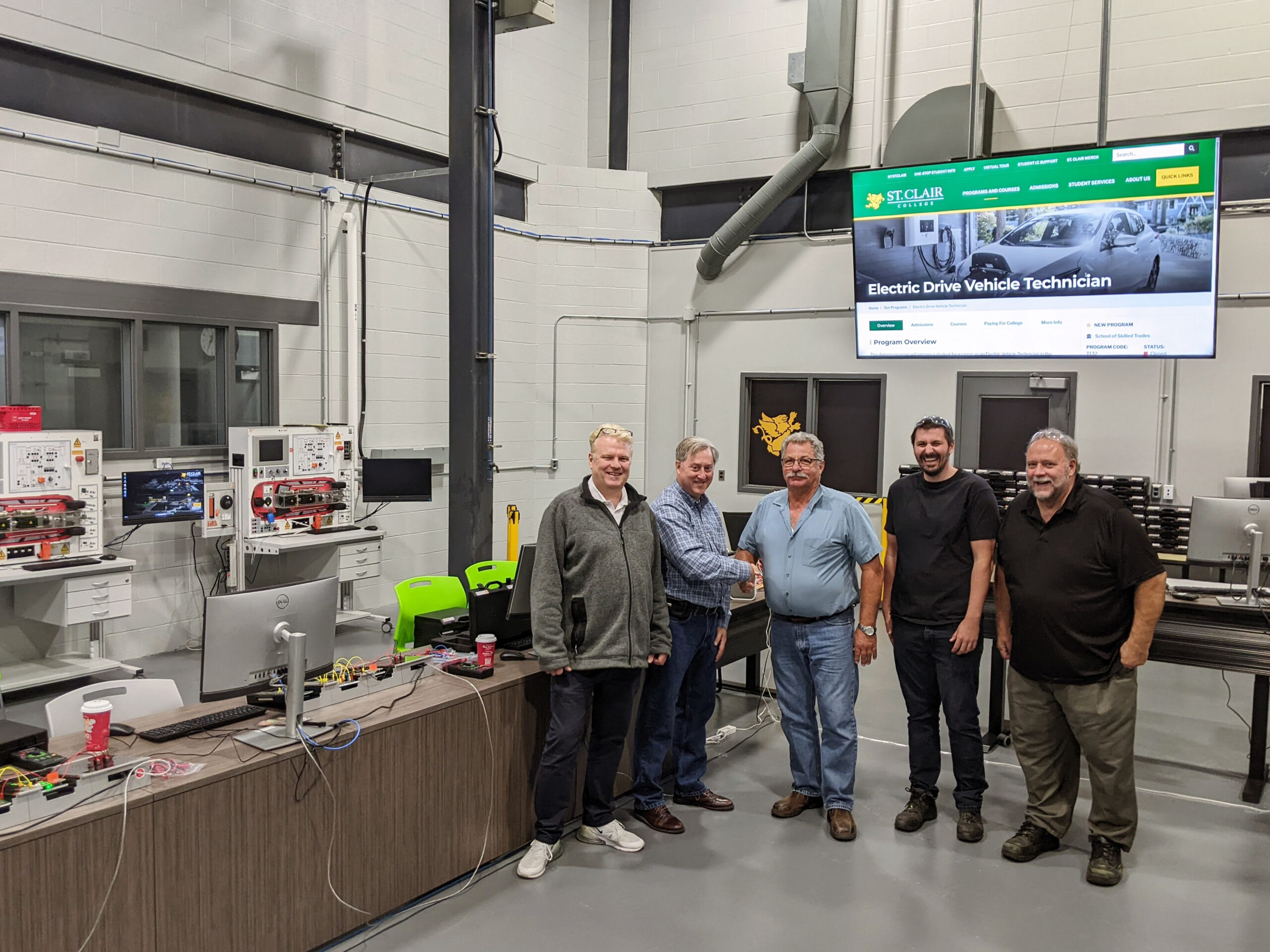 5 Personen am St. Clair College in Kanada stehen neben Kfz-Trainingssystemen von Lucas-Nülle.