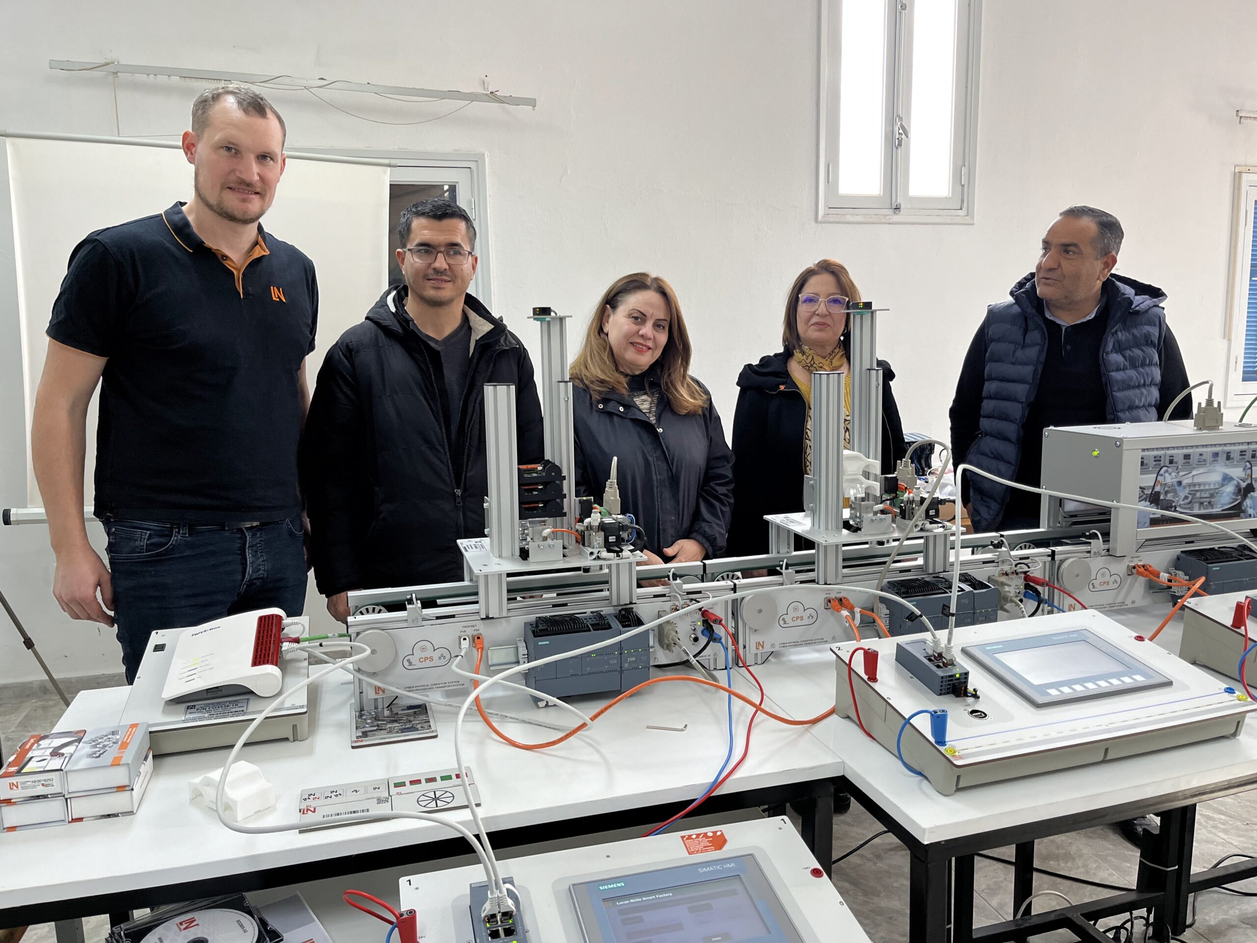 5 Personen stehen vor einer Industrie-4.0-Trainingsanlage